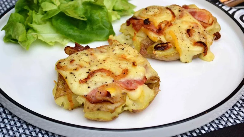 Pommes de terre au fromage à raclette, lard fumé et oignons grillés